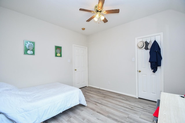 bedroom with light wood-style floors, a ceiling fan, and baseboards