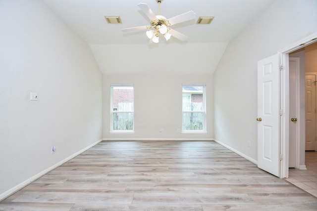 spare room featuring a ceiling fan, visible vents, light wood finished floors, and vaulted ceiling