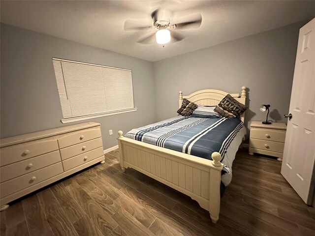 bedroom with a ceiling fan, baseboards, and dark wood-type flooring