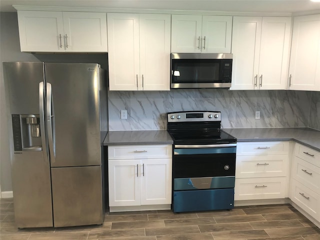 kitchen with dark wood finished floors, appliances with stainless steel finishes, white cabinets, and tasteful backsplash