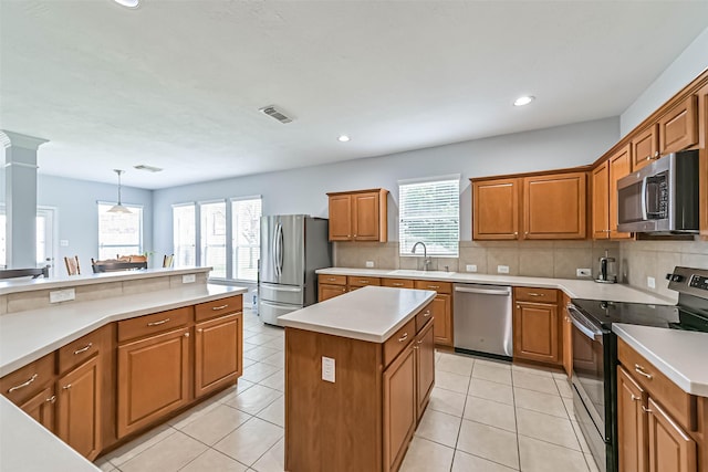 kitchen featuring brown cabinetry, decorative backsplash, visible vents, a sink, and appliances with stainless steel finishes