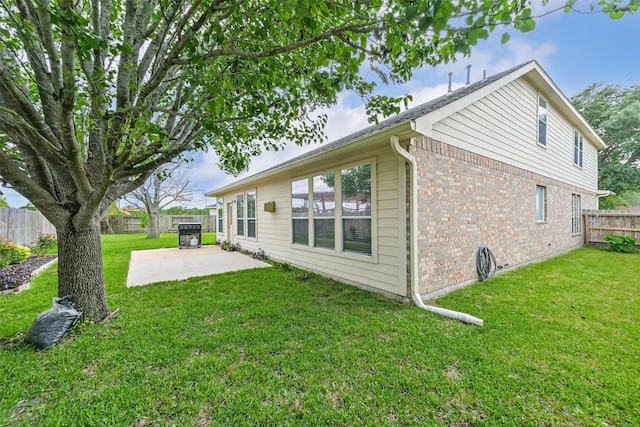 back of house featuring a fenced backyard, a yard, a patio area, and brick siding