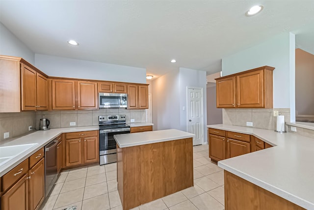 kitchen with light countertops, appliances with stainless steel finishes, a kitchen island, and tasteful backsplash