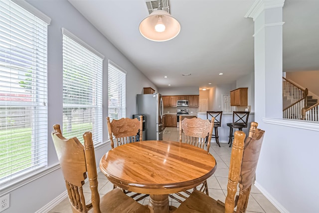 dining room with visible vents, baseboards, light tile patterned floors, and stairway