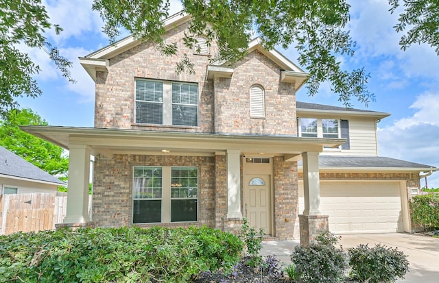 traditional-style house with a garage, fence, brick siding, a porch, and driveway