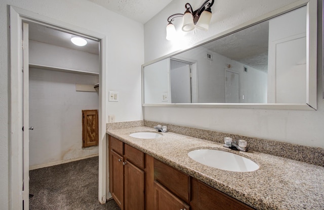 bathroom with double vanity, a sink, a textured ceiling, and visible vents