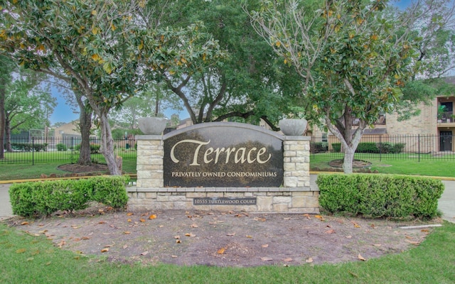 community sign featuring a lawn and fence