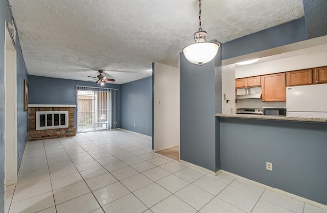kitchen featuring a ceiling fan, freestanding refrigerator, stainless steel microwave, and light tile patterned flooring