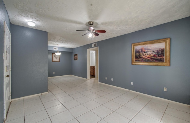 spare room featuring light tile patterned floors, a textured ceiling, visible vents, and ceiling fan