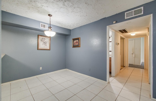spare room with visible vents, a textured ceiling, and light tile patterned floors