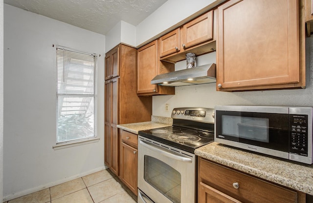 kitchen featuring plenty of natural light, appliances with stainless steel finishes, light tile patterned flooring, and wall chimney range hood