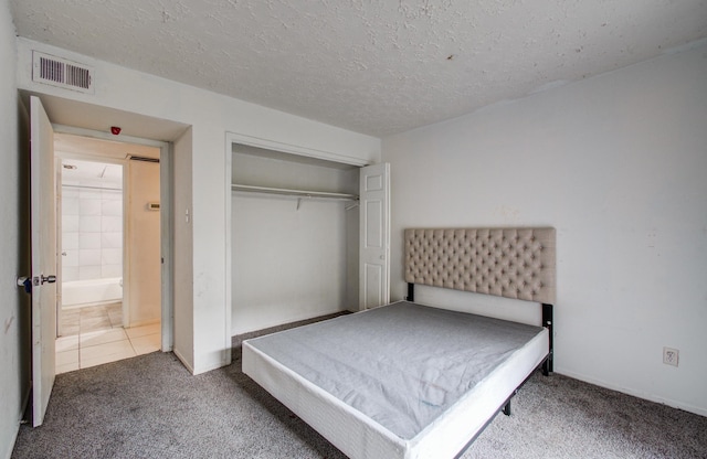 carpeted bedroom with a closet, a textured ceiling, and visible vents