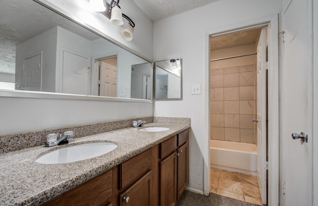 bathroom with double vanity, a textured ceiling, shower / washtub combination, and a sink