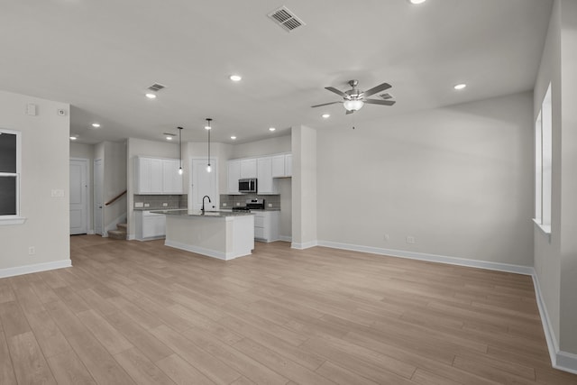 kitchen with visible vents, open floor plan, ceiling fan, a sink, and appliances with stainless steel finishes