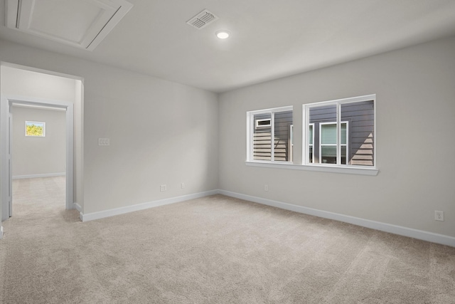 unfurnished room with baseboards, light carpet, attic access, and visible vents