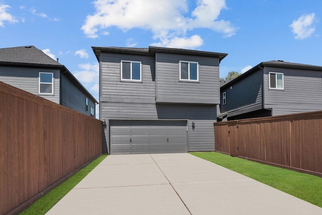rear view of house with fence, an attached garage, and driveway