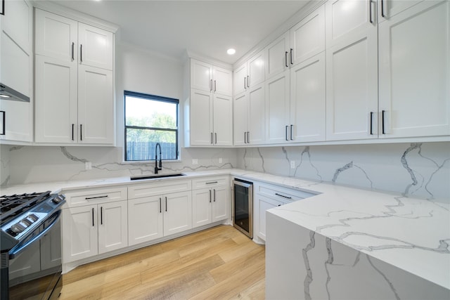 2420 Sumpter St, Houston, TX 77026 - kitchen featuring black gas range, wine cooler, light wood-style floors, white cabinets, and a sink