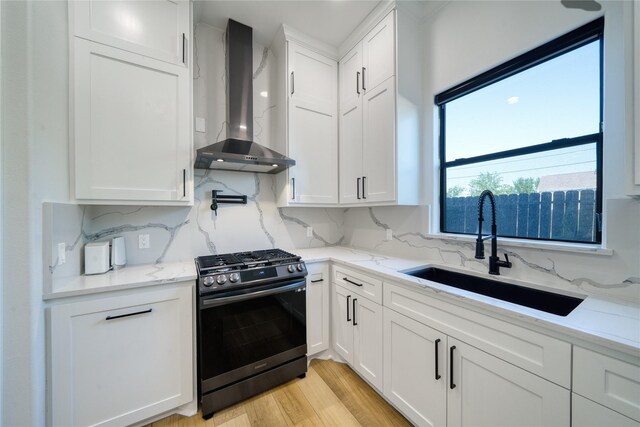 2420 Sumpter St, Houston, TX 77026 - kitchen with a sink, wall chimney exhaust hood, gas range, and white cabinetry