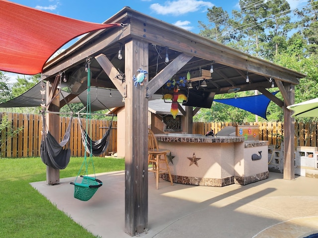 view of patio featuring a gazebo, a fenced backyard, and outdoor dry bar