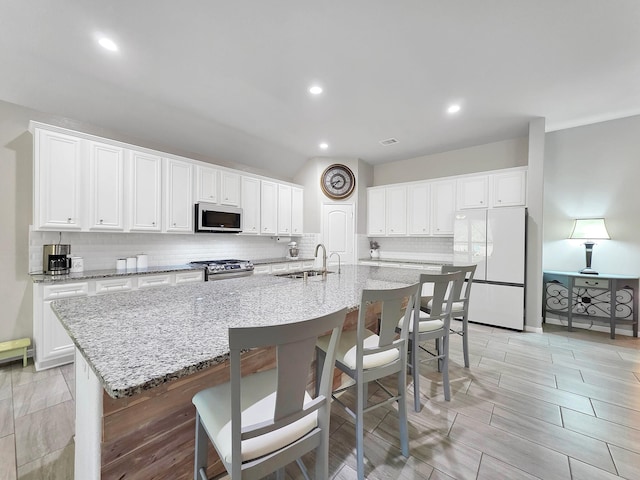 kitchen featuring a sink, decorative backsplash, white cabinets, and stainless steel appliances