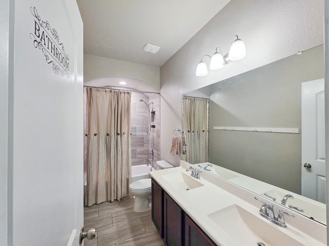 bathroom with double vanity, toilet, a sink, and shower / bath combo