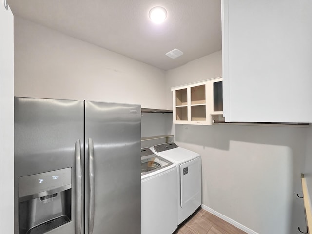 laundry area with independent washer and dryer, laundry area, baseboards, and light wood-type flooring