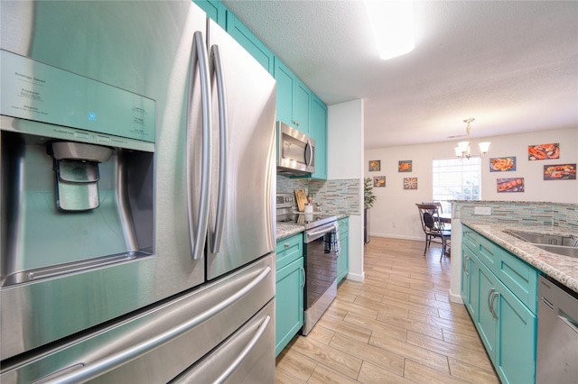 10912 Gulf Fwy Unit 28, Houston, TX 77034 - kitchen featuring appliances with stainless steel finishes, tasteful backsplash, a chandelier, pendant lighting, and light wood-style floors