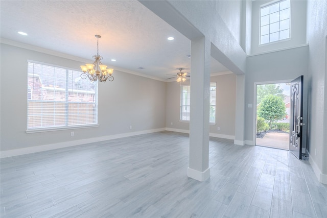 foyer featuring light wood-style floors, baseboards, plenty of natural light, and ceiling fan with notable chandelier