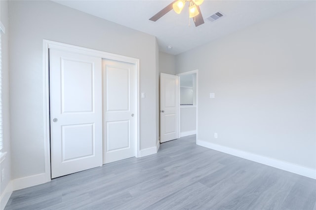 unfurnished bedroom with baseboards, a closet, light wood-style flooring, and visible vents