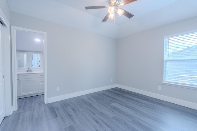 empty room with light wood-style floors, a sink, baseboards, and a ceiling fan