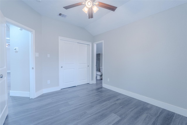 unfurnished bedroom featuring visible vents, wood finished floors, baseboards, a closet, and lofted ceiling