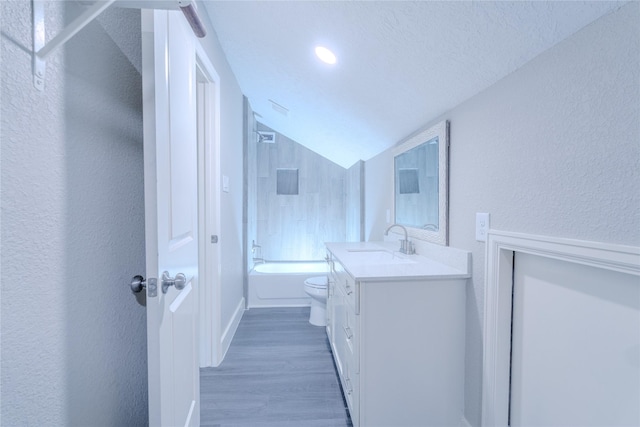 bathroom with a textured wall, bathtub / shower combination, vanity, toilet, and lofted ceiling
