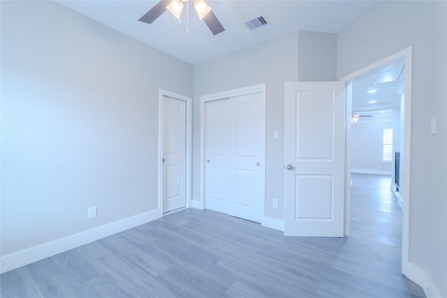 unfurnished bedroom featuring a ceiling fan, baseboards, wood finished floors, visible vents, and a closet