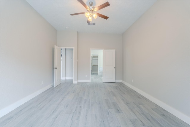 unfurnished bedroom with baseboards, visible vents, a walk in closet, and light wood-type flooring