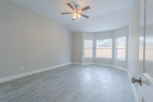 unfurnished room with wood finished floors, baseboards, ceiling fan, a textured ceiling, and vaulted ceiling