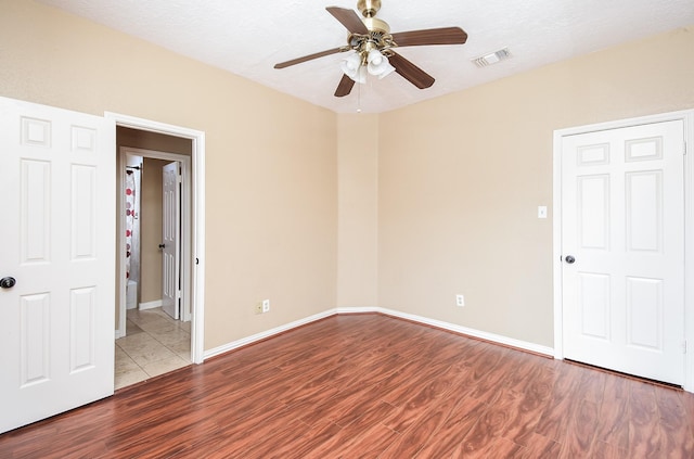 unfurnished bedroom featuring a ceiling fan, baseboards, visible vents, and wood finished floors