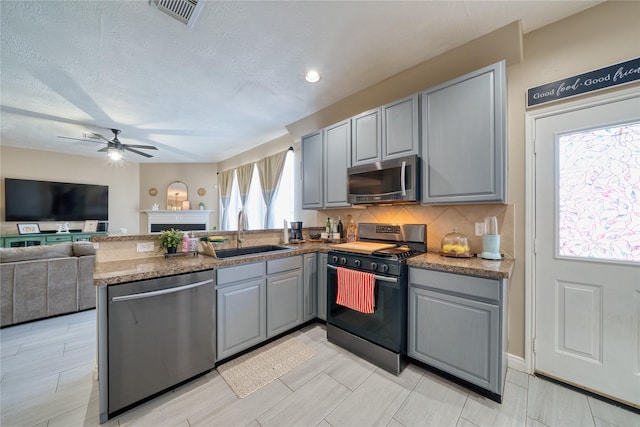 kitchen with visible vents, a sink, appliances with stainless steel finishes, and gray cabinetry