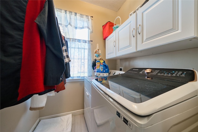 washroom featuring baseboards, cabinet space, and independent washer and dryer