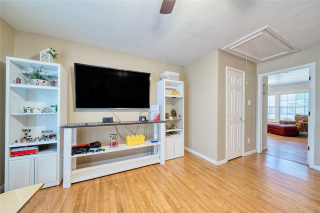 living room with a ceiling fan, baseboards, wood finished floors, and attic access