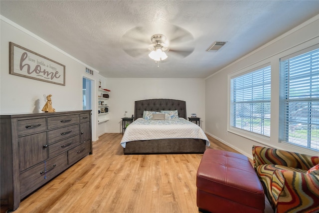 bedroom with crown molding, a ceiling fan, light wood finished floors, and visible vents