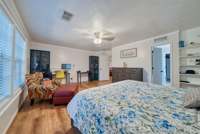 bedroom with a ceiling fan, visible vents, ornamental molding, and wood finished floors