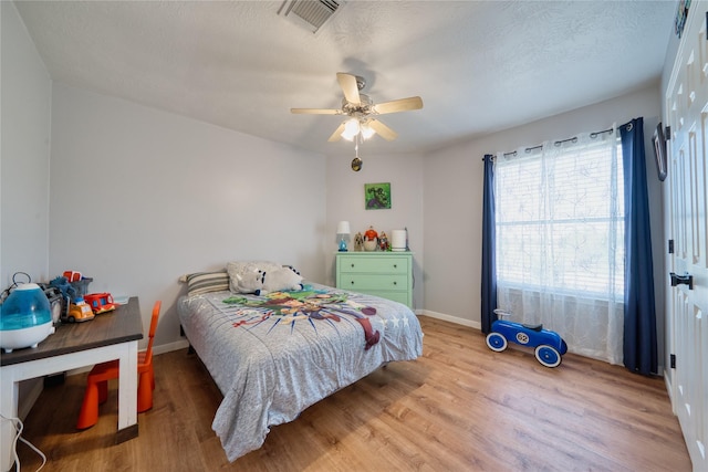bedroom with visible vents, baseboards, ceiling fan, and wood finished floors
