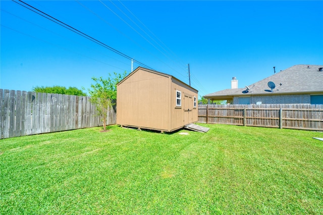 view of yard with an outbuilding, a fenced backyard, and a shed