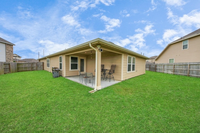 rear view of property featuring a lawn, a fenced backyard, and a patio