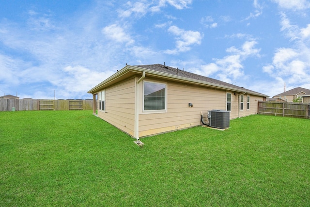 rear view of property with a lawn, central AC unit, and a fenced backyard