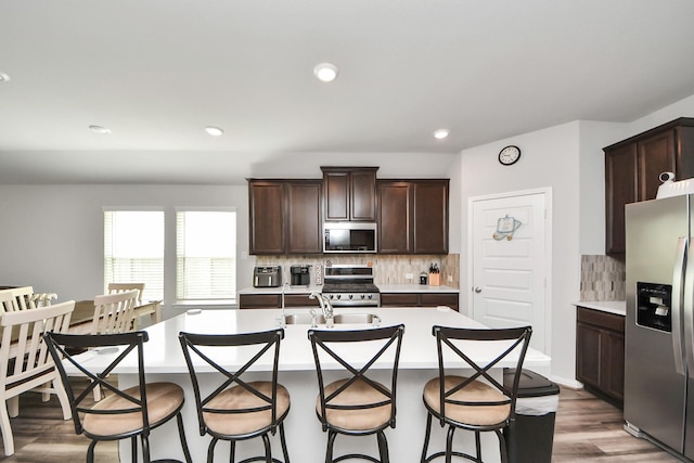kitchen featuring light countertops, appliances with stainless steel finishes, dark brown cabinets, and tasteful backsplash