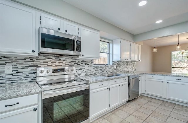kitchen with a sink, appliances with stainless steel finishes, white cabinetry, and a healthy amount of sunlight