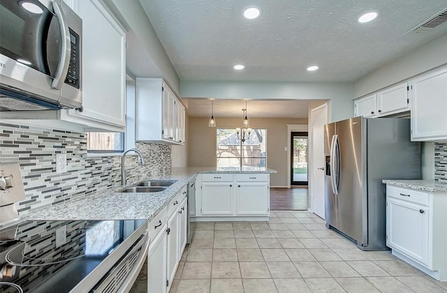 kitchen featuring a peninsula, a sink, appliances with stainless steel finishes, and white cabinetry