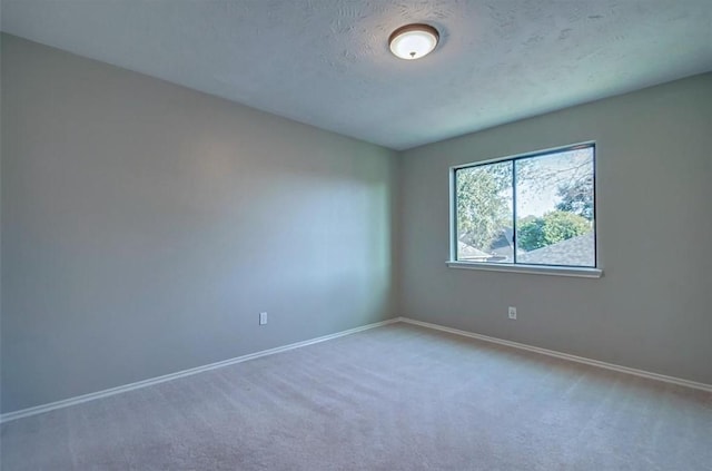 carpeted spare room with baseboards and a textured ceiling
