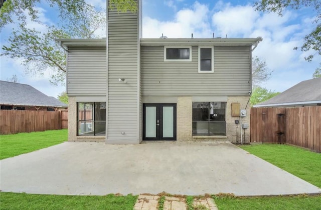 rear view of house featuring a patio, a fenced backyard, french doors, a chimney, and a yard